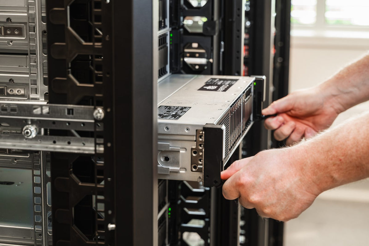 To hender skyver en server inn på skinnene i et rack